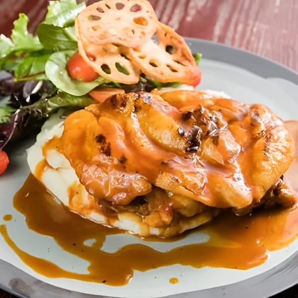 Peruvian chicken with orange sauce over mashed potatoes, served with a side salad and lotus root chips.