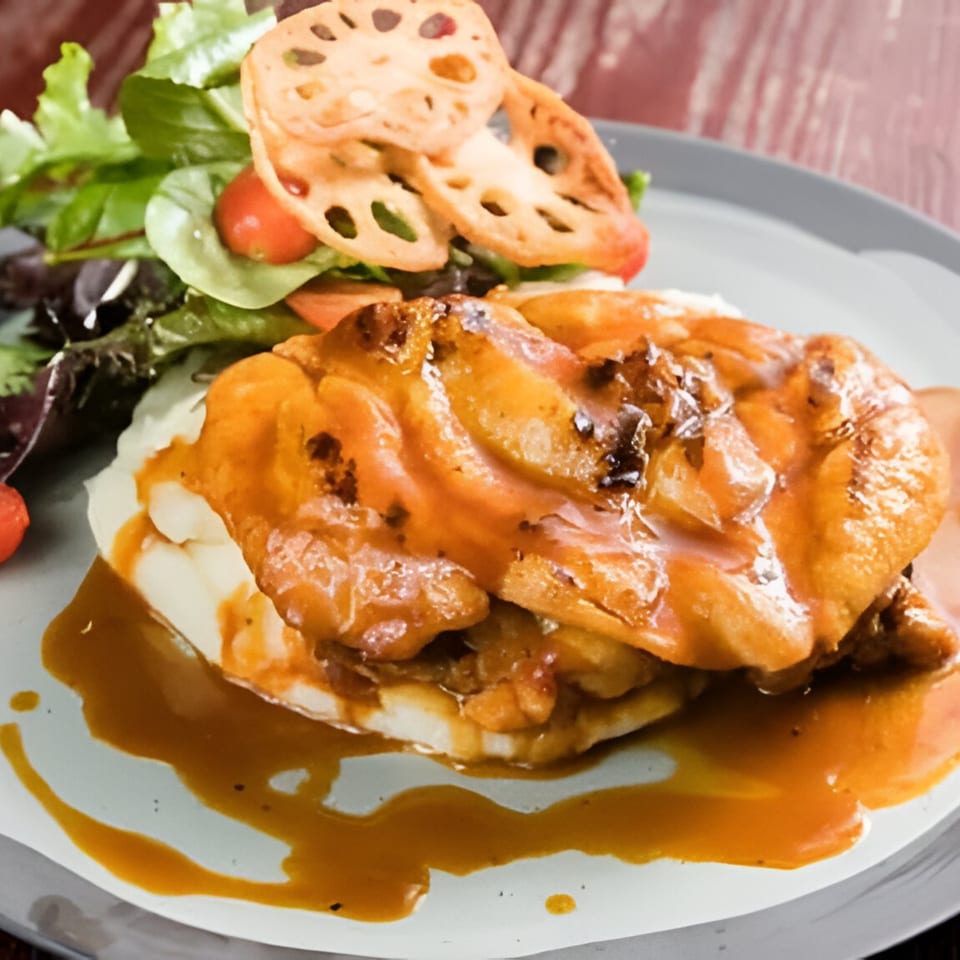 Peruvian chicken with orange sauce over mashed potatoes, served with a side salad and lotus root chips.